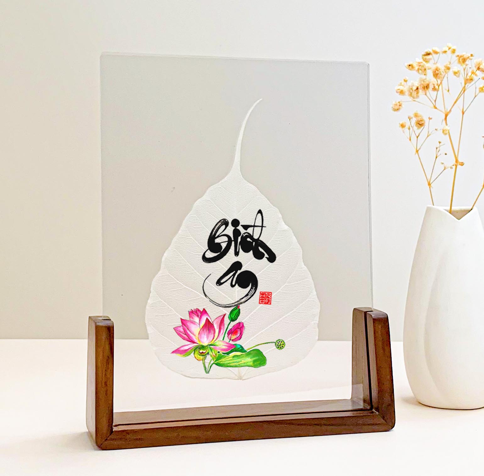 Pink lotus and Bình An calligraphy printed on a Bodhi leaf in a desk frame